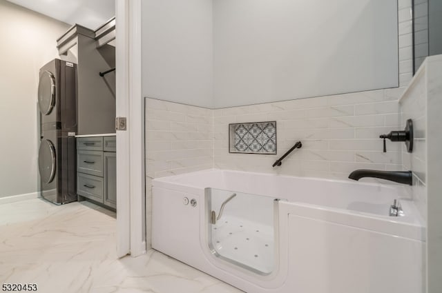 bathroom featuring a bathtub and stacked washer / dryer