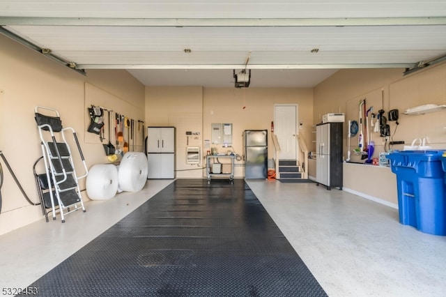 garage featuring a garage door opener, white fridge, and stainless steel fridge