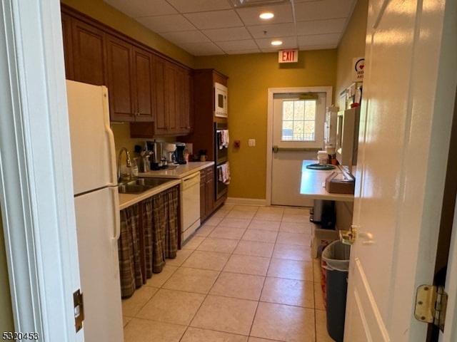 kitchen with white appliances, light tile patterned floors, and sink