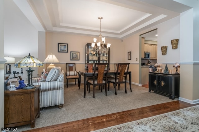 dining area with a chandelier, hardwood / wood-style flooring, and a raised ceiling