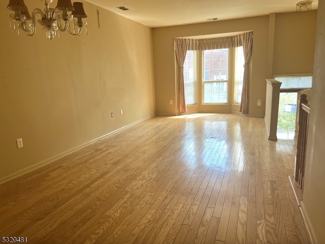 unfurnished living room with a chandelier and light hardwood / wood-style flooring