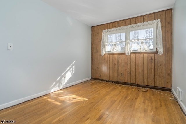 empty room with wooden walls and light wood-type flooring