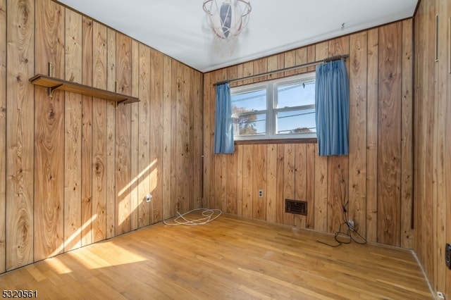 spare room featuring wood walls and light hardwood / wood-style flooring