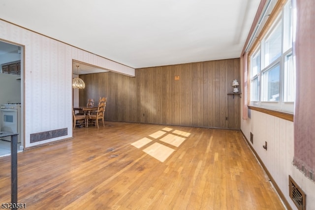 spare room with wood walls, light hardwood / wood-style flooring, and a notable chandelier