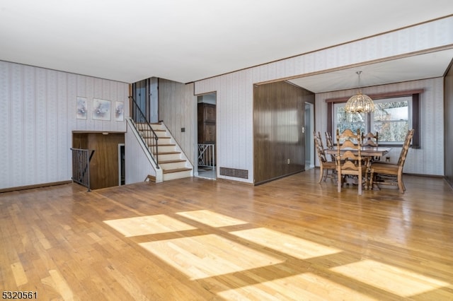 unfurnished dining area featuring wood walls, hardwood / wood-style floors, and a notable chandelier