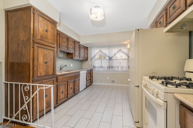 kitchen featuring backsplash, sink, and white appliances