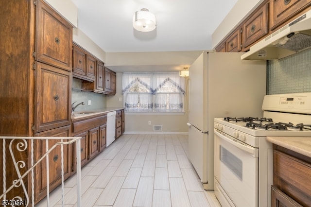 kitchen featuring decorative backsplash, white appliances, and sink