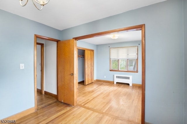 unfurnished bedroom featuring a closet, hardwood / wood-style flooring, and radiator