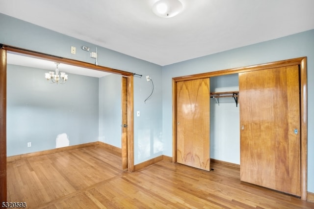 unfurnished bedroom featuring a closet, an inviting chandelier, and wood-type flooring