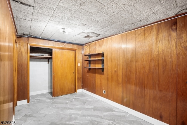 unfurnished bedroom featuring a closet and wooden walls