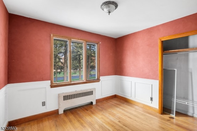 spare room featuring radiator heating unit and light wood-type flooring