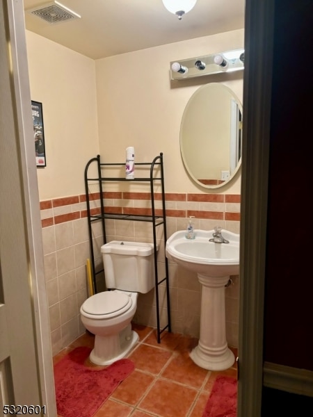 bathroom featuring toilet, tile walls, sink, and tile patterned flooring