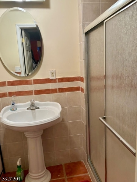 bathroom with a shower with door and tile walls