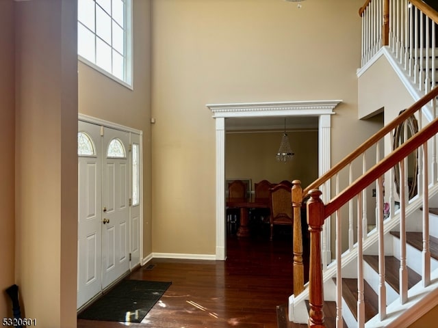 entryway with dark wood-type flooring, a high ceiling, and a chandelier