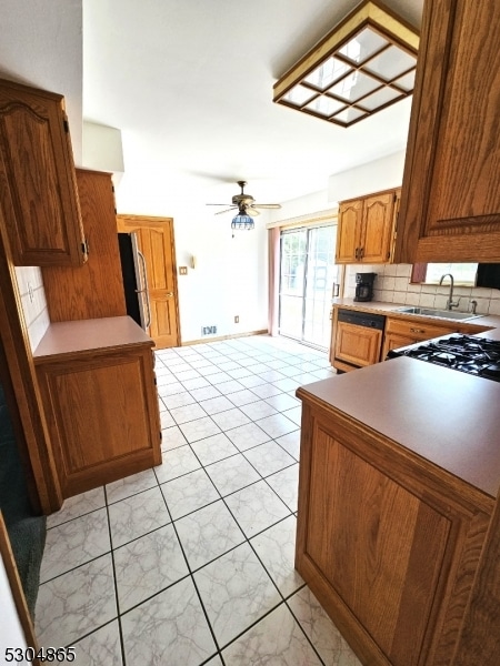 kitchen with backsplash, stainless steel refrigerator, sink, and ceiling fan