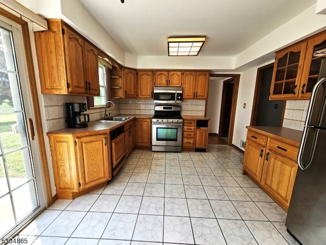 kitchen with appliances with stainless steel finishes, sink, and decorative backsplash