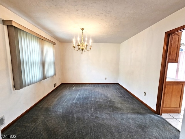 carpeted empty room featuring a textured ceiling and an inviting chandelier