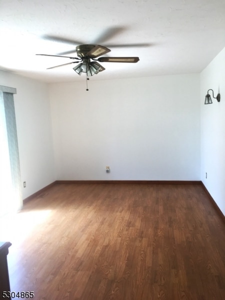 empty room with ceiling fan and dark hardwood / wood-style flooring