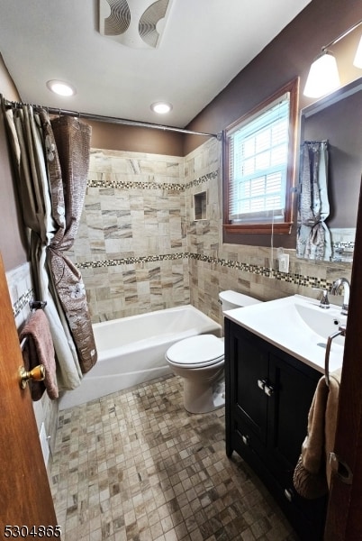 full bathroom featuring tile walls, vanity, shower / bath combo, and toilet