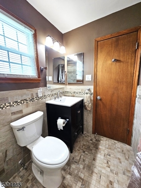 bathroom with vanity, toilet, and tile walls