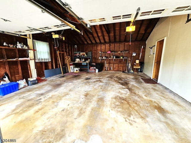 garage featuring a garage door opener and wood walls