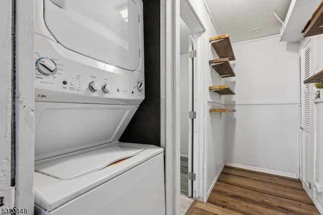 laundry room featuring stacked washing maching and dryer and dark wood-type flooring