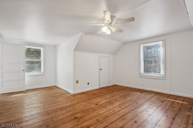 additional living space with lofted ceiling, hardwood / wood-style flooring, and a healthy amount of sunlight