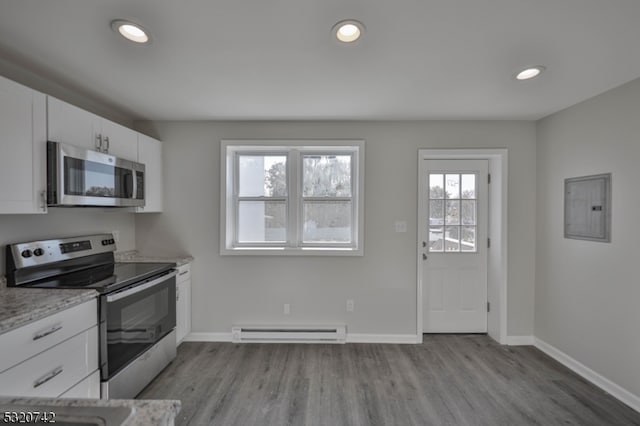 kitchen with baseboard heating, stainless steel appliances, plenty of natural light, electric panel, and white cabinets