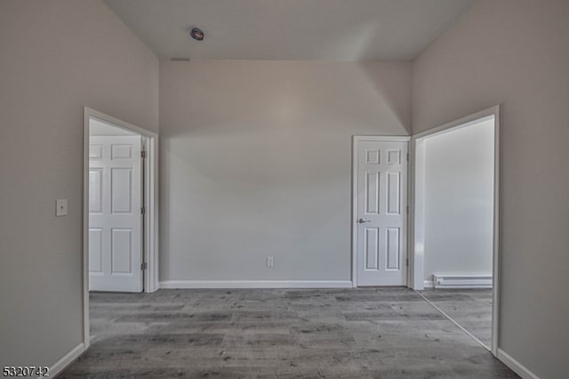 unfurnished room with light hardwood / wood-style floors, a high ceiling, and a baseboard radiator