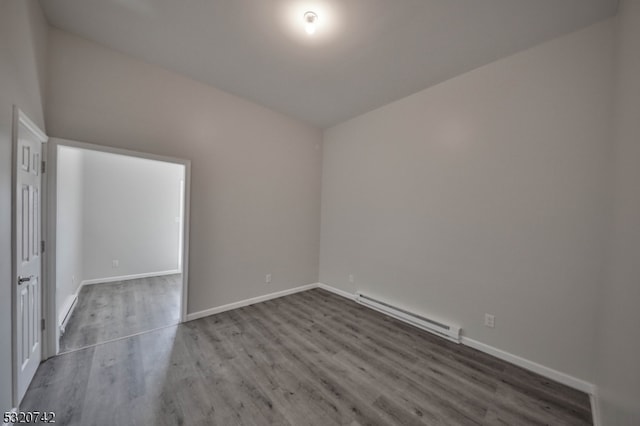 unfurnished room with a baseboard radiator, hardwood / wood-style floors, and lofted ceiling