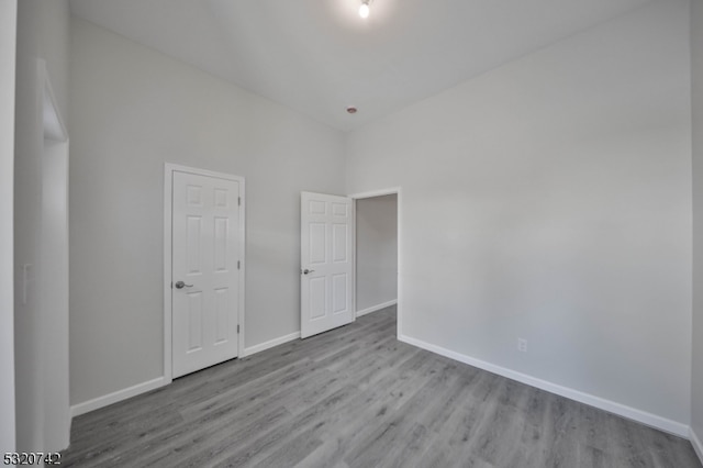 empty room featuring light hardwood / wood-style floors and a towering ceiling