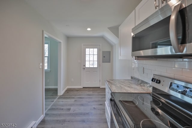 kitchen featuring tasteful backsplash, appliances with stainless steel finishes, light wood-type flooring, white cabinets, and electric panel