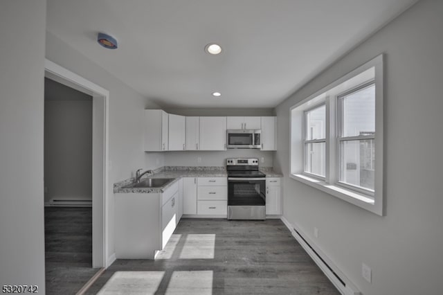 kitchen featuring hardwood / wood-style floors, appliances with stainless steel finishes, white cabinetry, baseboard heating, and sink