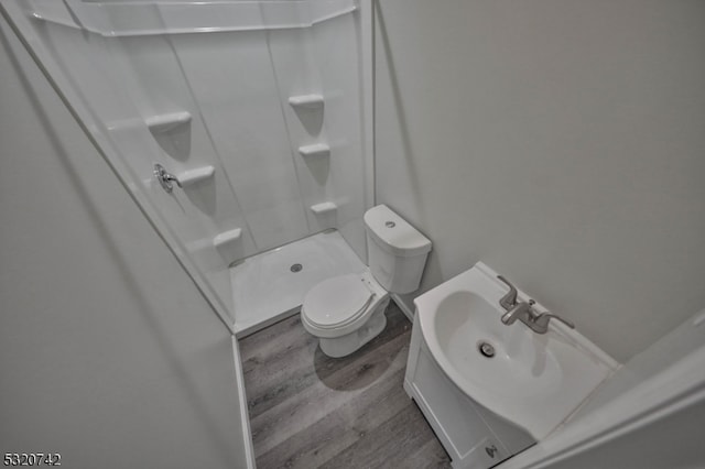 bathroom featuring toilet, a shower, and hardwood / wood-style floors