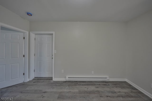 unfurnished room featuring baseboard heating and light hardwood / wood-style floors