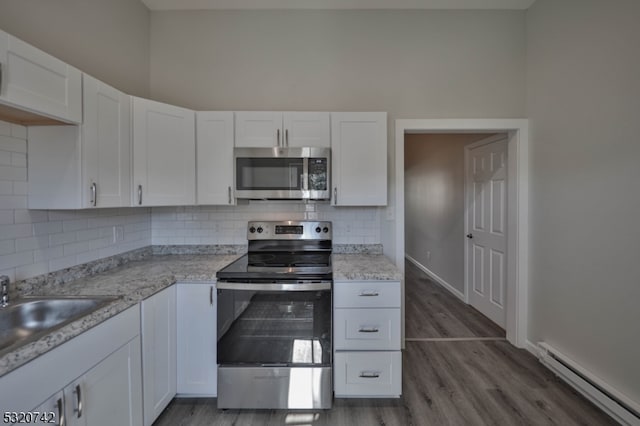 kitchen with backsplash, dark hardwood / wood-style flooring, white cabinetry, stainless steel appliances, and baseboard heating