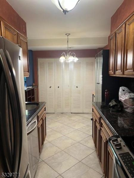 kitchen featuring a chandelier, decorative light fixtures, stainless steel appliances, and light tile patterned flooring