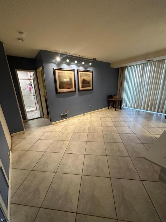 empty room featuring light tile patterned floors and track lighting