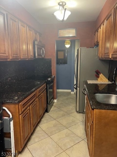 kitchen featuring black / electric stove, sink, light tile patterned floors, and dark stone counters