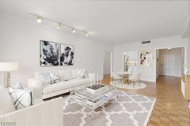 living room with track lighting, ornamental molding, and light parquet floors