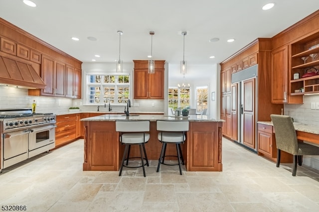 kitchen featuring a kitchen island, high quality appliances, backsplash, decorative light fixtures, and light stone counters