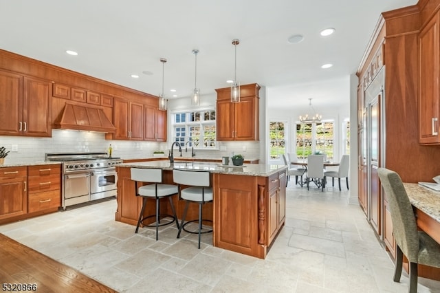 kitchen featuring a kitchen island with sink, a wealth of natural light, custom exhaust hood, and stainless steel stove