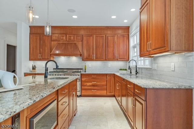 kitchen with hanging light fixtures, sink, custom exhaust hood, light stone counters, and tasteful backsplash