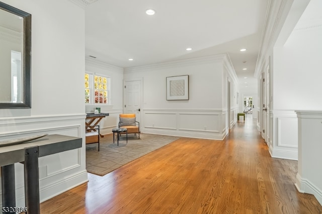 corridor with ornamental molding and light hardwood / wood-style flooring