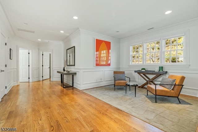 living area with light hardwood / wood-style floors and ornamental molding