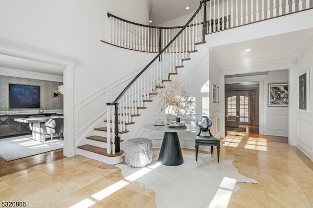 stairway featuring a high ceiling, crown molding, and french doors