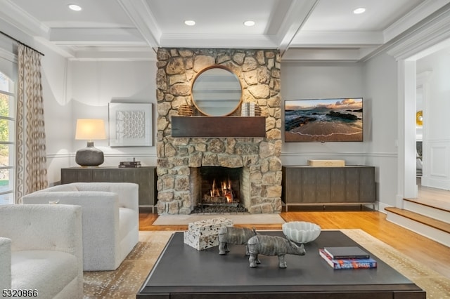 living room with light hardwood / wood-style floors, crown molding, beamed ceiling, and a fireplace