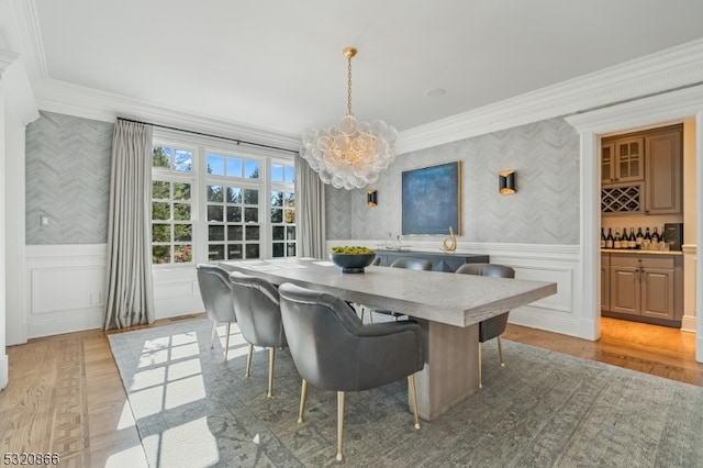 dining room featuring a notable chandelier, ornamental molding, and light hardwood / wood-style flooring