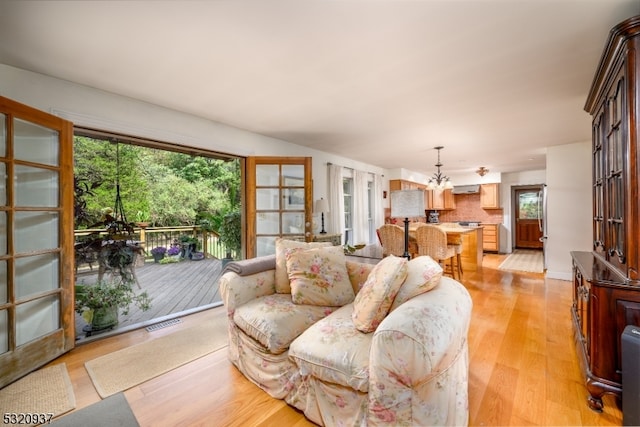 living room with light hardwood / wood-style flooring, a chandelier, and french doors