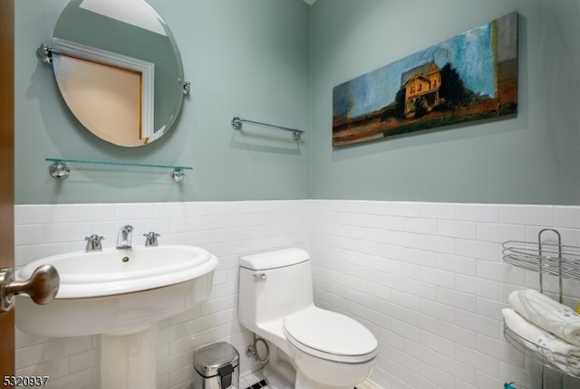 bathroom with sink, toilet, and tile walls